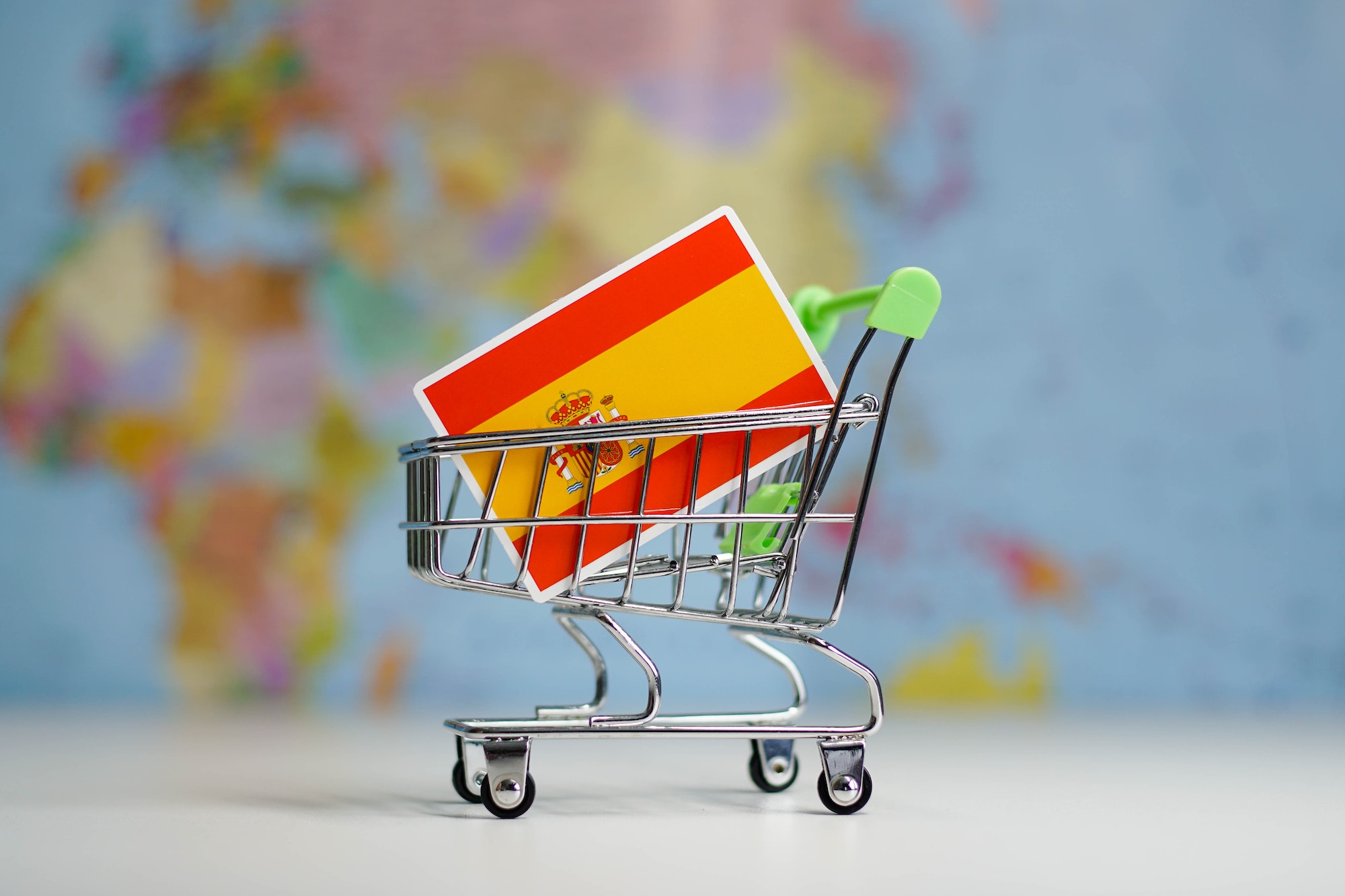 Spain national flag in miniature shopping trolley cart. Shopping online or shipping, duty concept.